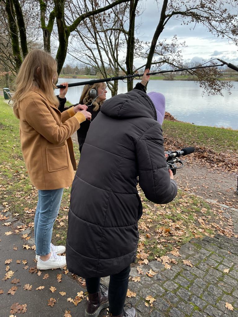 Die Filmcrew dreht am Seepark in Freiburg eine Szene. Zu sehen ist die Kamerafrau, die Mikrofonangel und die Tonfrau.